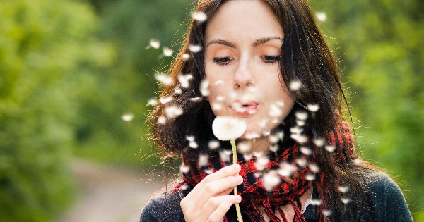 Woman blowing a dandelion in West Vancouver